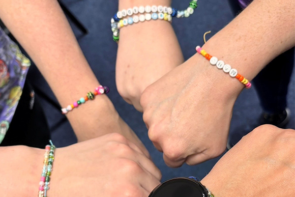Hände mit bunten Perlenarmbändern bilden einen Kreis